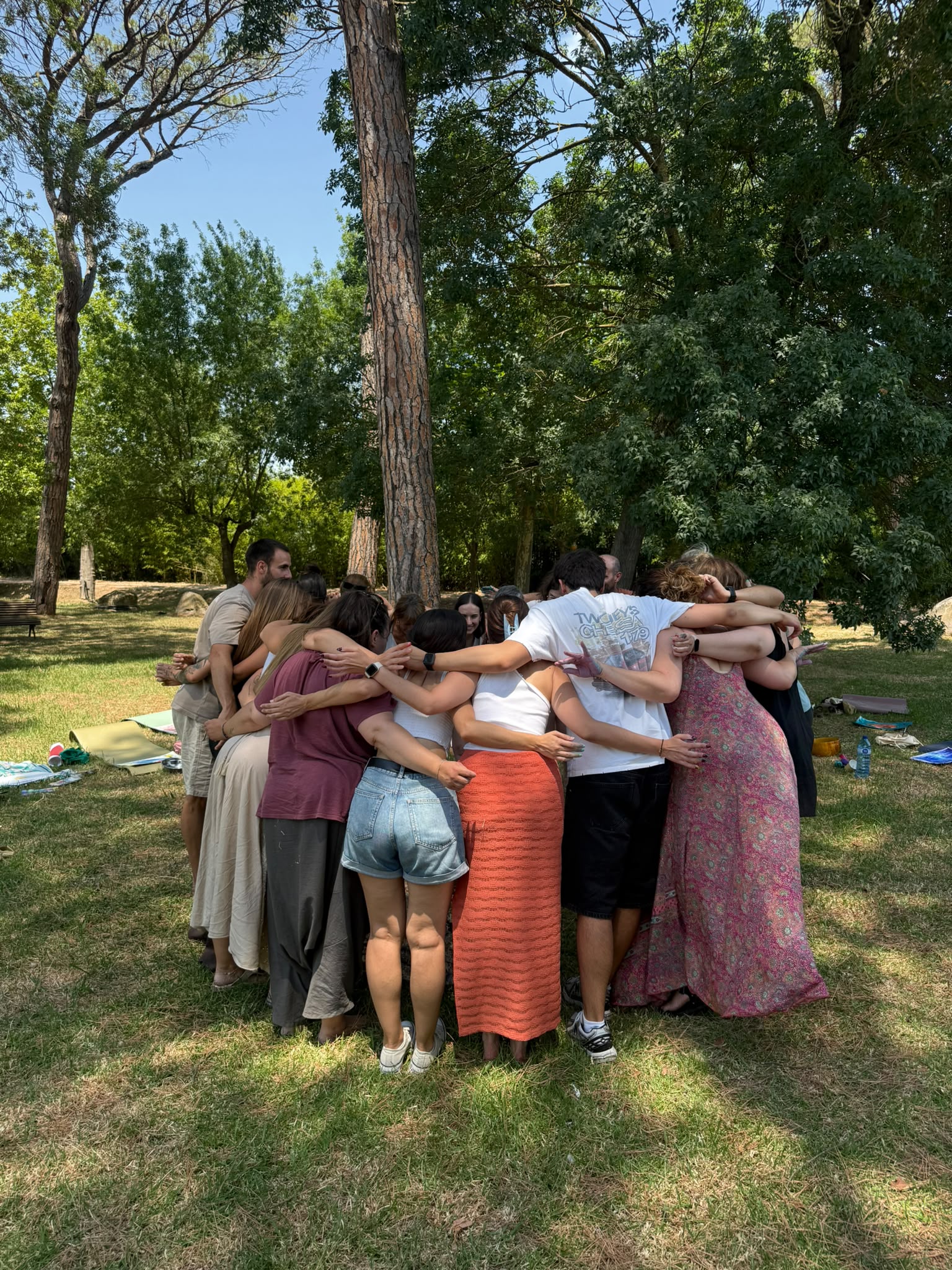 Un grup de persones s'abracen en cercle enmig d'un parc