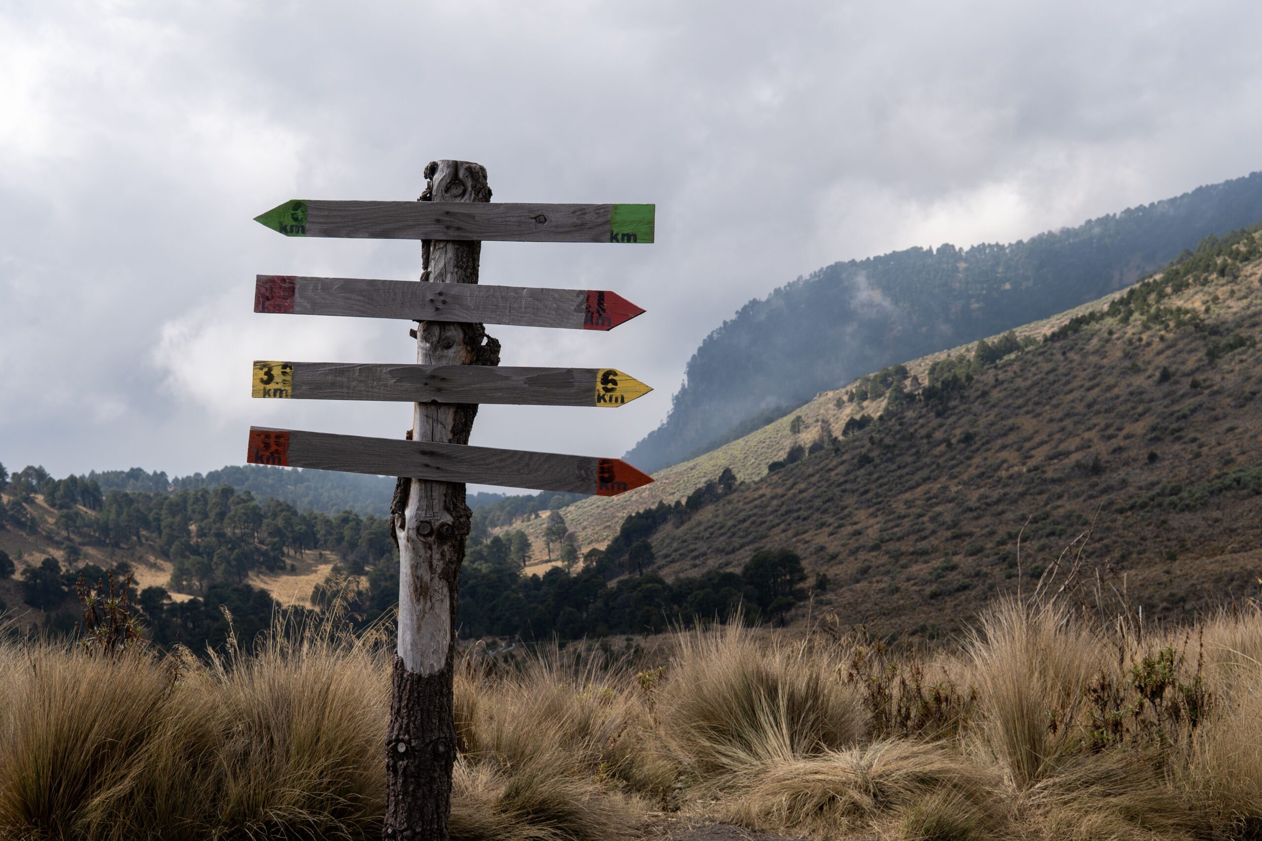 Un pal indicador amb diverses direccions en un paisatge de muntanya